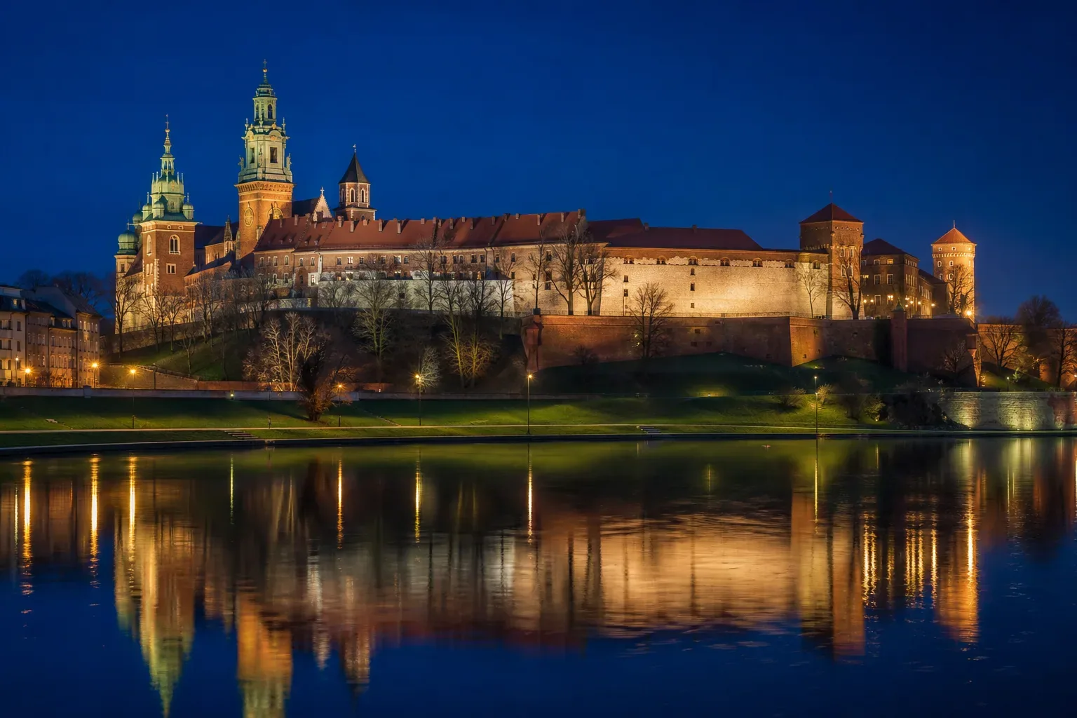 Wawel Castle and Cathedral above the Vistula river in Kraków, floodlit at dusk