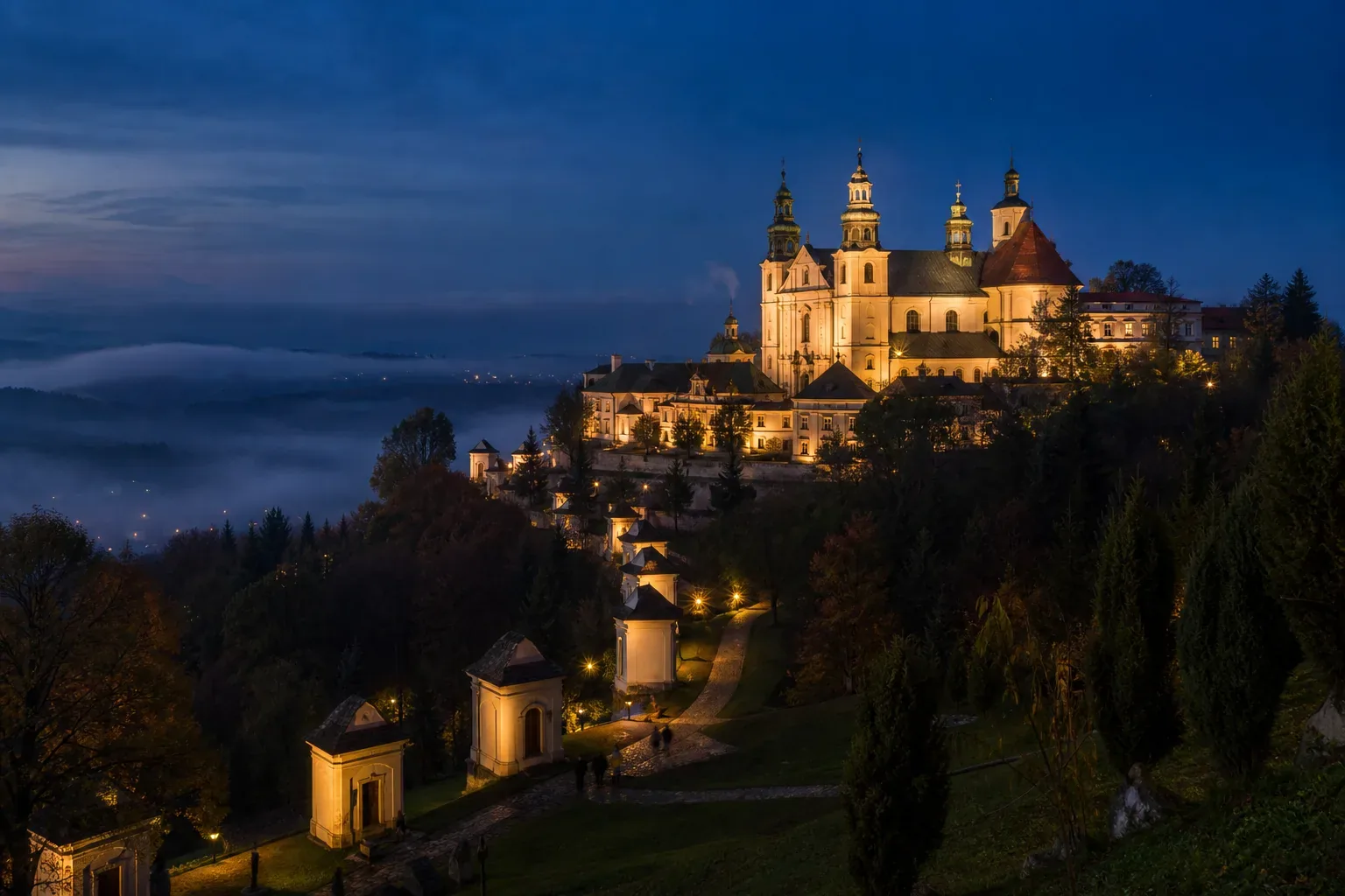 The basilica and monastery of Kalwaria Zebrzydowska on a wooded hillside above a misty valley